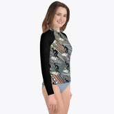 Child in a long-sleeved Surfer's Paradise rash guard featuring a fun cartoon graphic